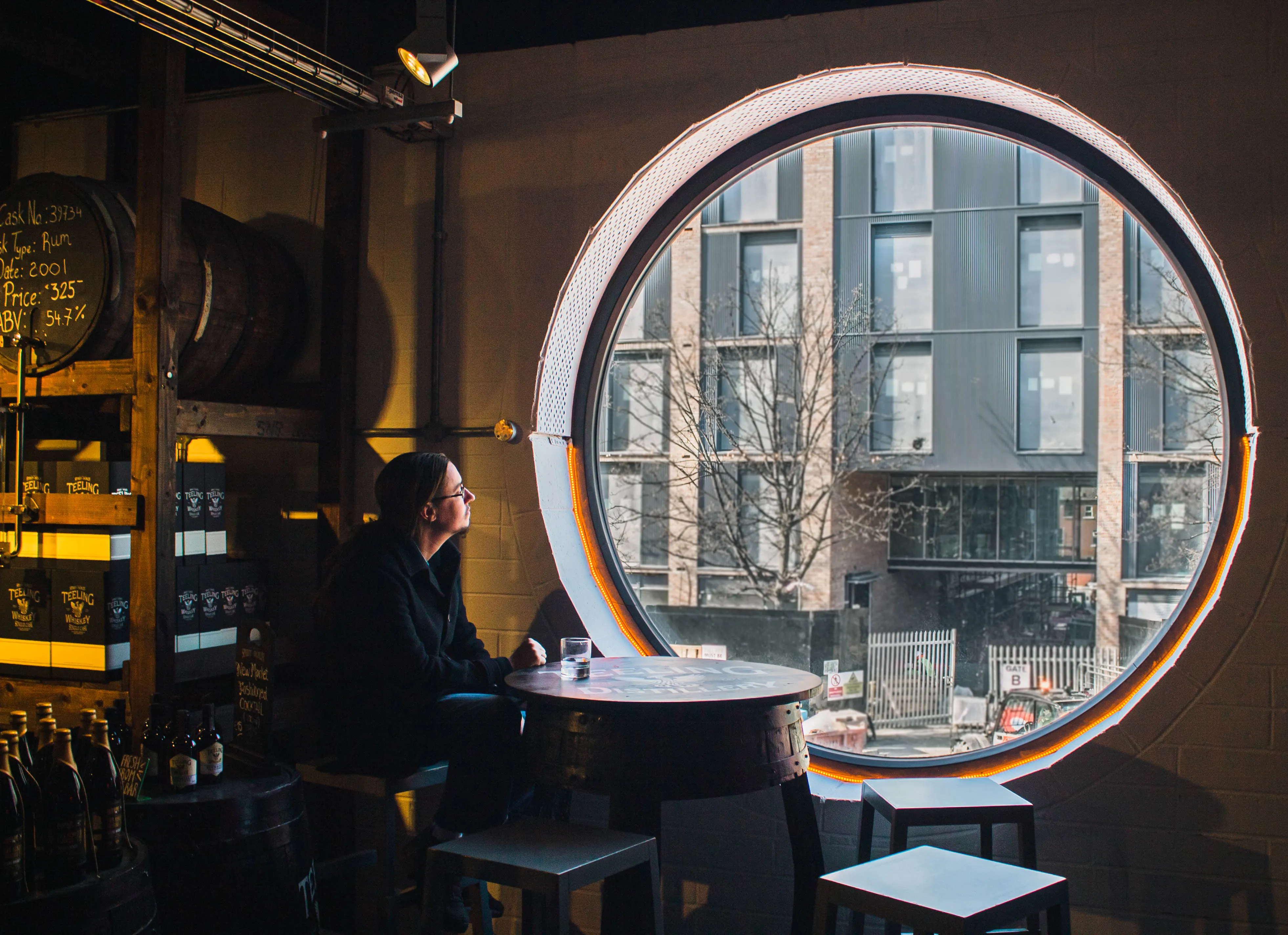 A man stares out a window in a whiskey distillery